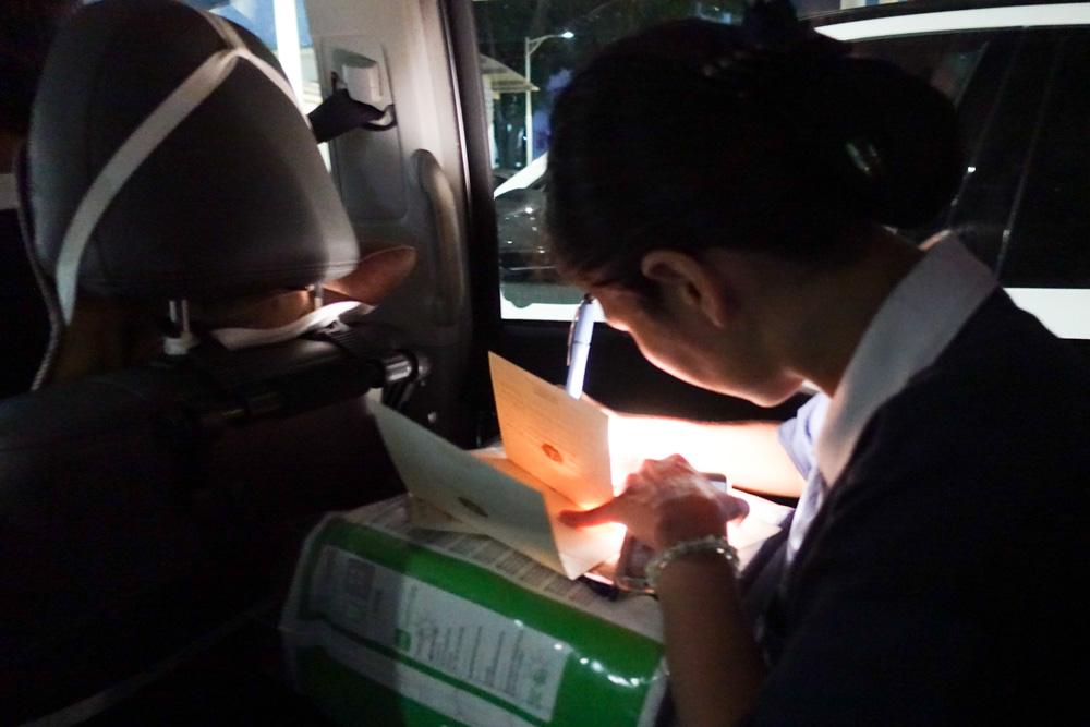 A volunteer seize time in the car to pen down words of blessings onto the greeting cards. (Photo by Bernard Ng Jia Han) 