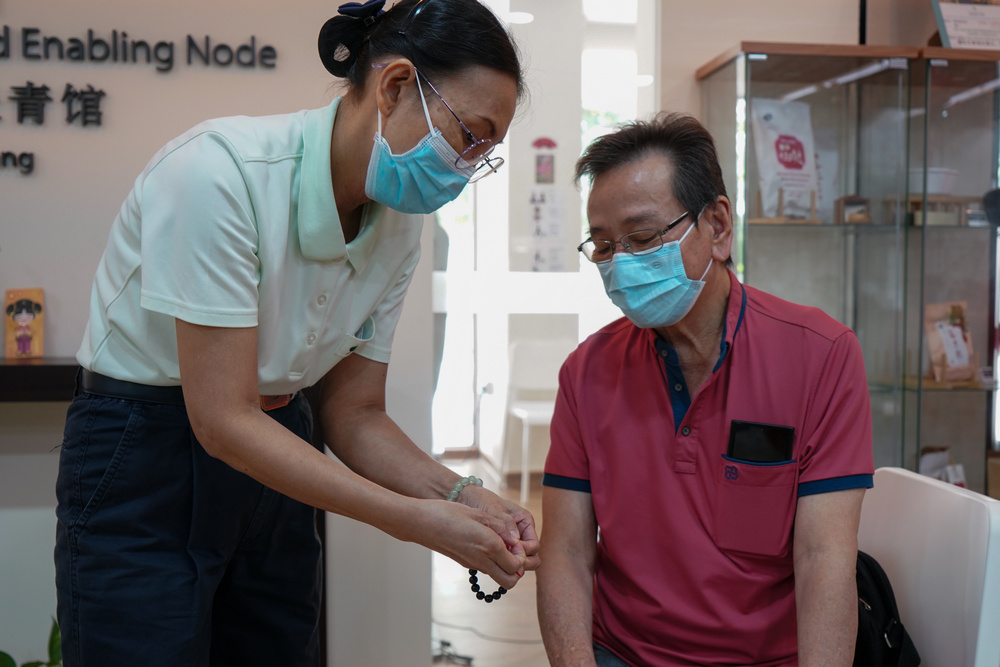 SEEN staff Ms Karen Loi (left) helping out a senior during the bracelet-making activity. (Photo by Chan May Ching)